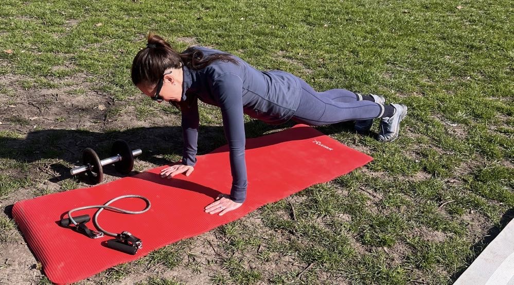 A fitness enthusiast doing a plank exercise next to training equipment at George Green Wanstead